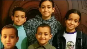 طفلة حزينة تجلس أمام منزل ريفي في دلجا، تعبيرًا عن الحزن بسبب المرض الغامض في المنيا