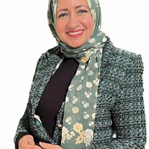 الإعلامية الدكتورة شيرين الشافعي بملابس رسمية وحجاب أخضر مشجر.