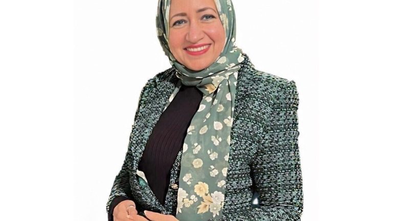 الإعلامية الدكتورة شيرين الشافعي بملابس رسمية وحجاب أخضر مشجر.