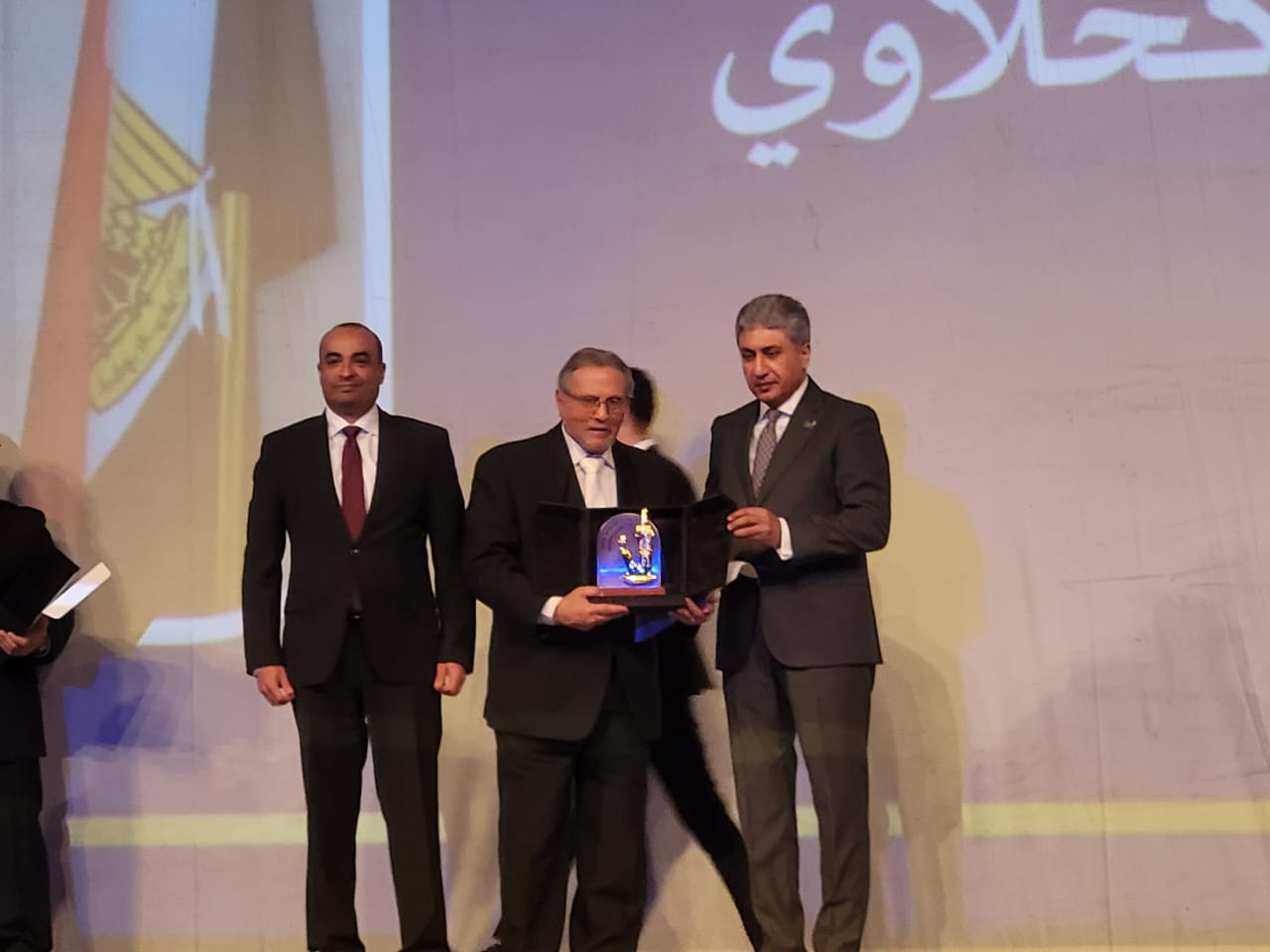 لحظة تسليم الوزير شريف فتحي درع التكريم للدكتور محمد الكحلاوي رئيس مجلس الآثاريين العرب