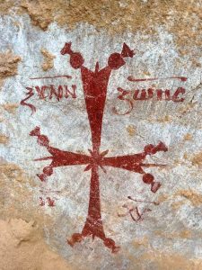 نقوش بالخط القبطي وصليب مزخرف على جدار الدير الأثري