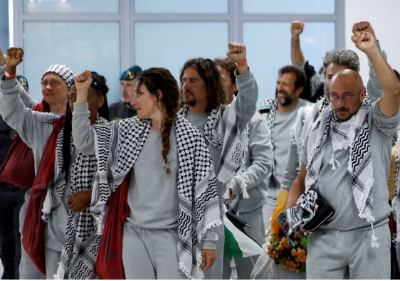 ناشطو أسطول الصمود العالمي يرفعون أيديهم عند وصولهم لمطار إسطنبول بعد ترحيلهم من إسرائيل